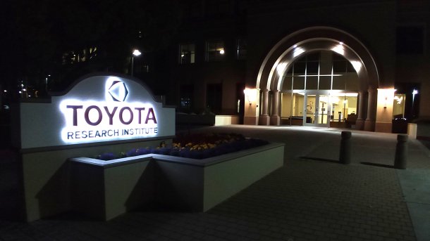 Eingangsbereich mit beleuchtetem Schild "Toyota Research Institute" bei Nacht