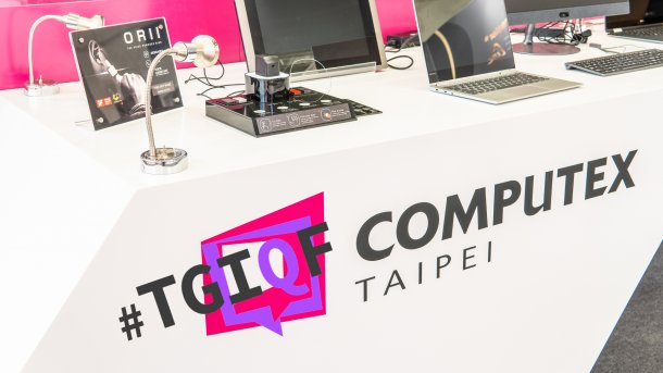Tisch mit Aufschrift "#TGIQF Computex Taipei", darauf einige elektronischen Geräte