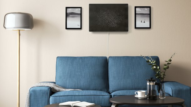 Wohnzimmerszene - schwarzer Lautsprecher hängt zwischen zwei Bildern an der Wand