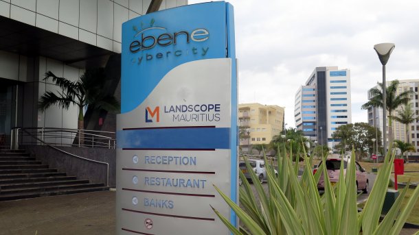 Schild "Ebene Cybercity" vor Hochhäusern, danabend tropische Pflanzen