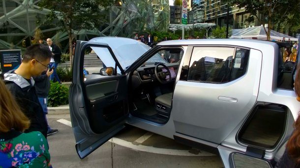 Rivian mit offener Seitentür und Fronthaube, dahinter das Amazon-Hauptquartier