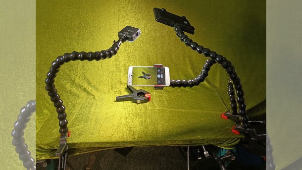 Fotostudio-Aufbau mit drei Loc-Line-Stativen für Lichter und Smartphone mit Kamera.