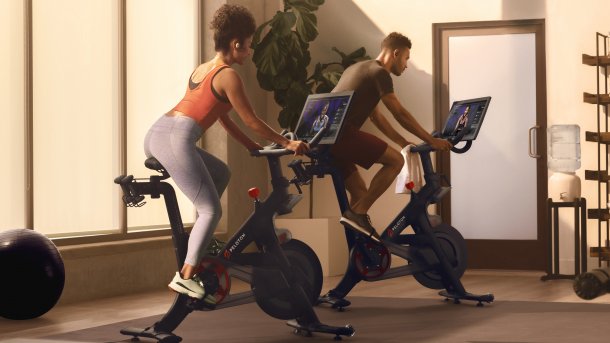 Frau trainiert mit Gewichten, Fitnessbike im Hintergrund