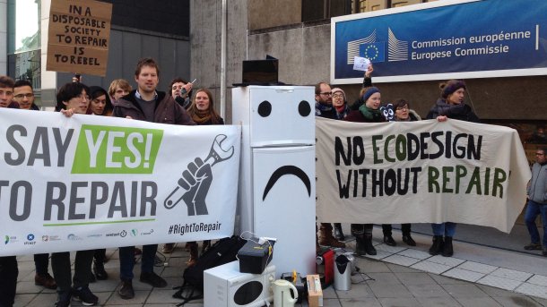 Vor einem Gebäude der Europäischen Kommission protestieren Menschen mit Plakaten für das Recht auf Reparatur