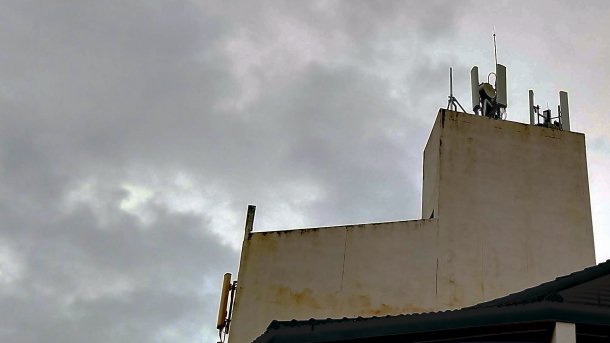 Mobilfunkantennen auf einem Malaysischen Gebäudedach, darüber dunkle Wolken
