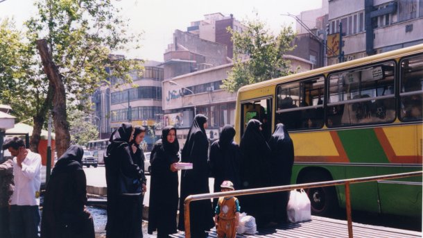 Eine Reihe schwarz verhüllter Frauen an einer Bushaltestelle