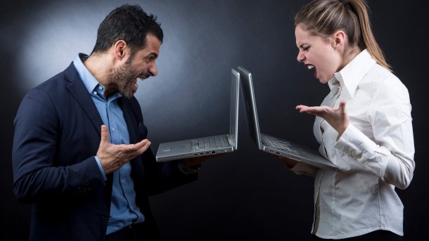 Personen mit Laptops stehen sich gegenüber und streiten