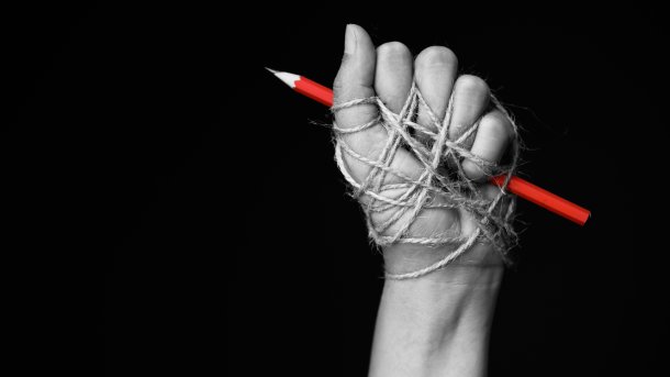 Hand,With,Red,Pencil,Tied,With,Rope,,Depicting,The,Idea