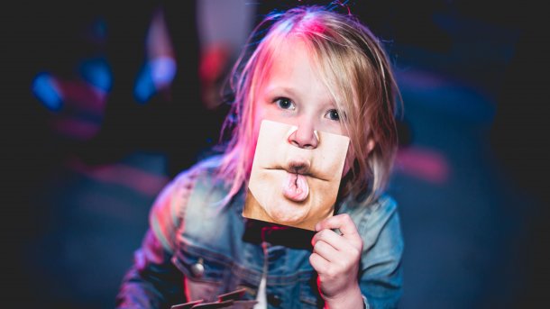 Kind hält sich Foto eines Mundes eines Erwachsenen vor den Mund
