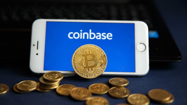 Ein Smartphone mit Coinbase-Schriftzug, mit Bitcoin-Münzen