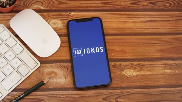 Ein Smartphone liegt auf dem Schreibtisch, auf dem Display das Ions-Logo