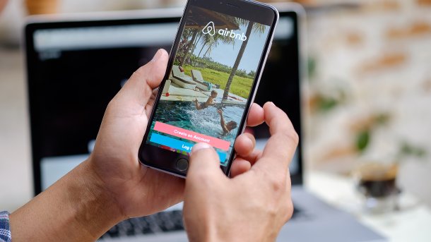 Mensch hälte Handy mit Airbnb-App