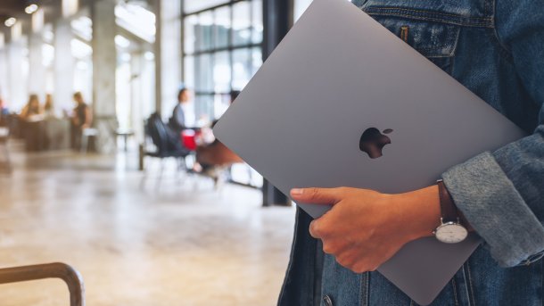 Eine Frau trägt zusammengeklapptes MacBook