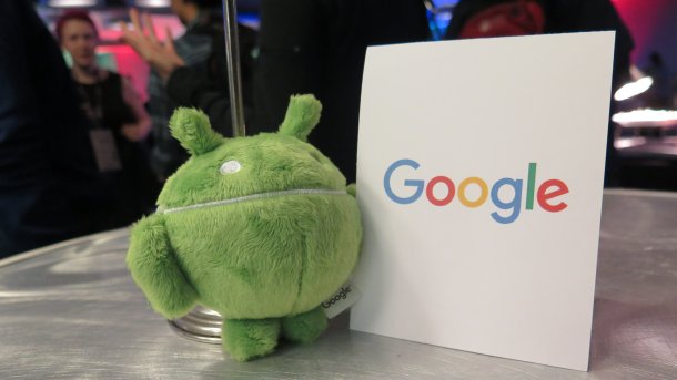 Grüner Plüsch-Androide neben Schild "Google"