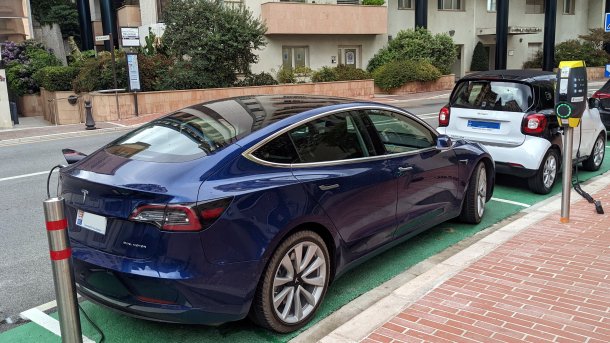 blaues Tesla-Auto mit monegassischem Kennzeichen parkt hinter einem weißen Smart