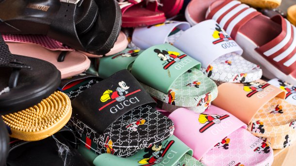 Badeschlappen, die mit gefälschtem "Gucci"-Logo und einer Micky Maus bedruckt sind, werden auf einem Markt in Manila zum Verkauf angeboten, 