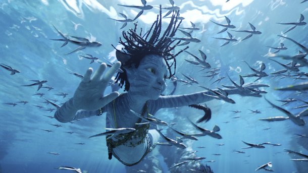Filmszene: Außerirdischer Humanoide unter Wasser, dazu viele kleine Fische