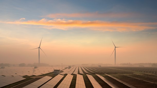 Windkraftanlagen hinter Solarpaneelen in der Landschaft