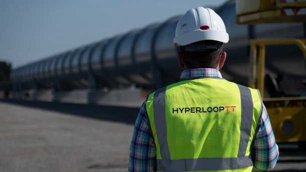 Mann in Arbeitskleidung, im Hintergrund eine Hyperloop-Röhre