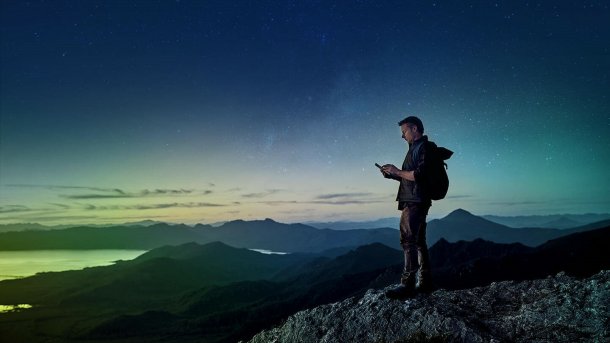 Mann mit Smartphone auf einem Berggipfel