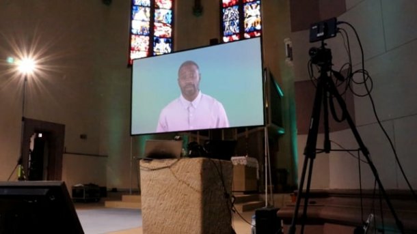 Bildschirm mit KI-Avatar in Kirche