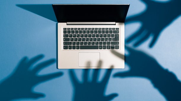 Schatten von vier Händen greifen nach einem Laptop