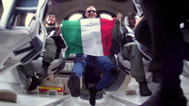 Schwebender Mann mit Sonnenbrille hält eine italienische Fahne in die Kamera