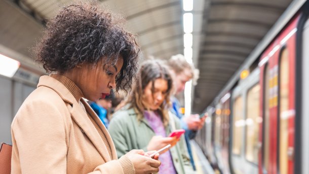 Menschen auf U-Bahn-Bahnsteig, die auf ihre Handys starren