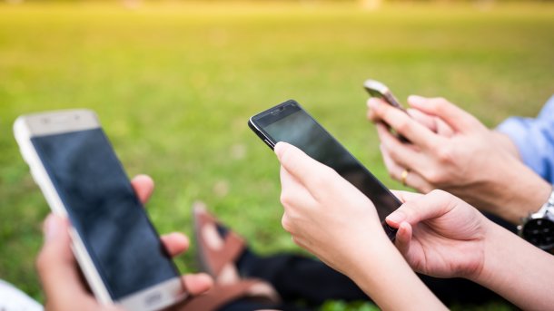 Menschengruppe hat Smartphones in den Händen, während sie bei einem Rapsfeld sind