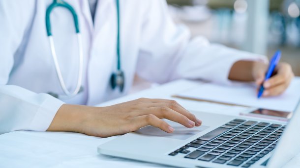 Doctor's,Hands,Typing,On,A,Laptop,And,Writing,On,Clipboard. Arzt, Digitalisierung, KIM