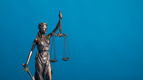 Statue der Justizia vor blauem Hintergrund