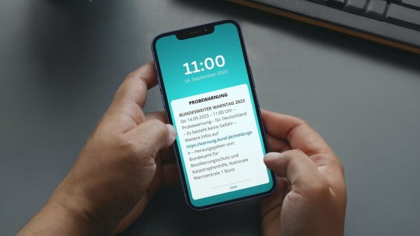 Smartphone in den Händen einer Person mit Cell-Broadcast Warnung (SMS-CB)