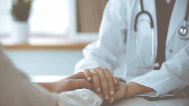 Ärztin hält Hand von Patientin