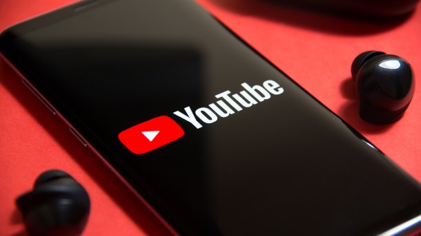 Ein Handy mit YouTube-Logo zwischen Kopfhörern