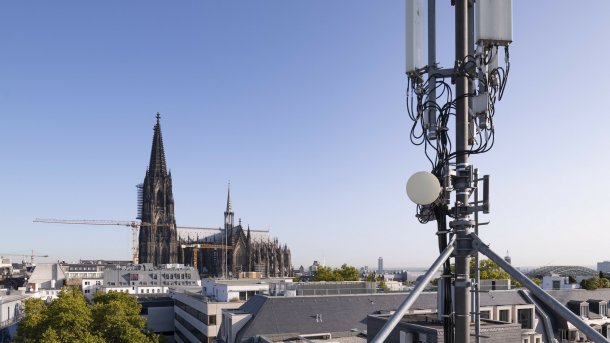 Eine Mobilfunkantenne auf einem Dach, im Hintergrund der Kölner Dom