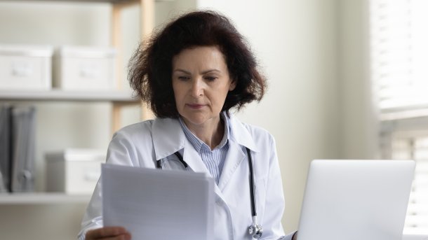 Ärztin mit Blatt Papier und Laptop