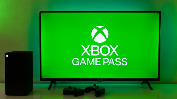 Xbox Game Pass Logo auf TV neben Xbox und Controllern