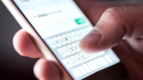 Mann mit Wurstfingern textet eine Nachricht auf einem Smartphone 
