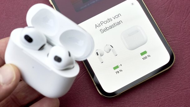 AirPods im geöffneten Akkukästchen vor einem iPhone