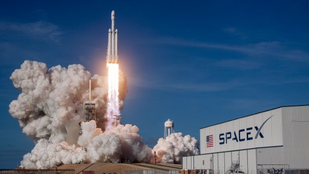 Startende Rakete hinter Halle mit SpaceX-Logo