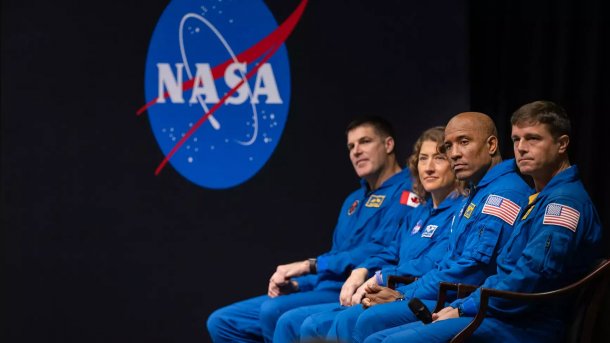 Vier Raumfahrer vor NASA-Logo