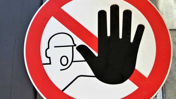 Verbotstafel: Eine gezeichnete Person mit Helm hält die Hand als "Stop"-Befehl hoch
