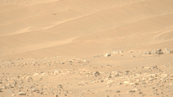 Orange-rote Sandlandschaft und ein kleiner Helikopter