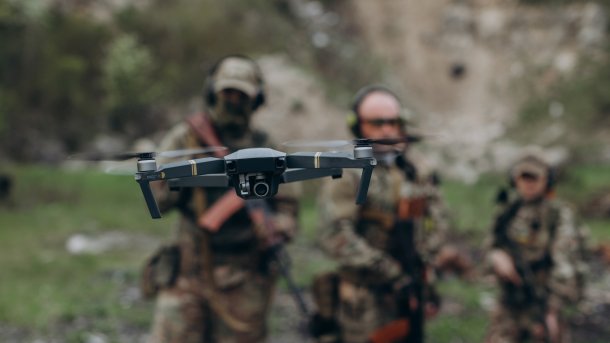 Drohne mit Soldaten im Hintergrund