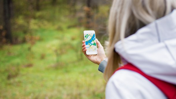 Eine Person navigiert mit dem Handy durch den Wald.