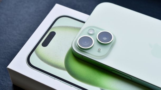 Ein grünes iPhone 15 liegt auf der Verpackung.