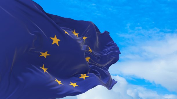 Die Flagge der EU weht im Wind vor blauem Himmel.