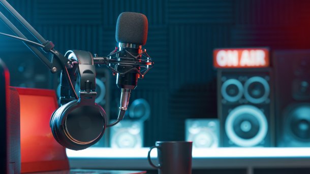 Kopfhörer und Mikrofon in einem Radiostudio, im Hintergrund leuchtet "On Air"