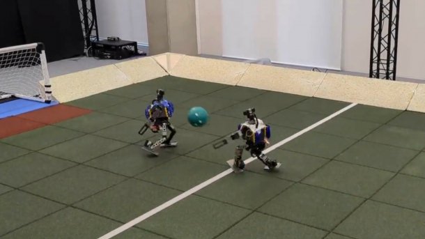 Zwei kleine OP3-Roboter spielen Fußball.