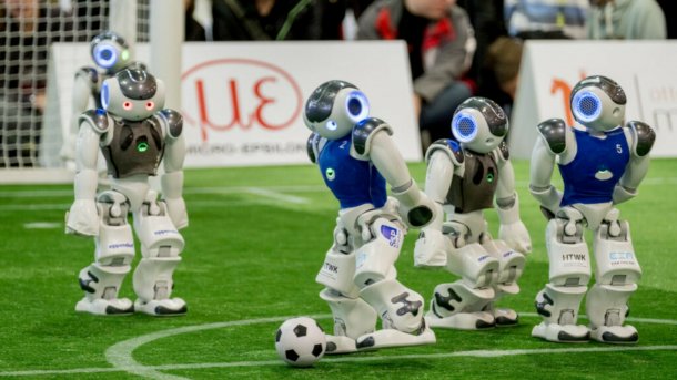 Vier Roboter spielen Fußball.
